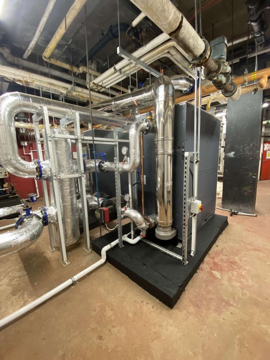 Plate heat exchanger and insulated distribution pipework in a commercial plant room