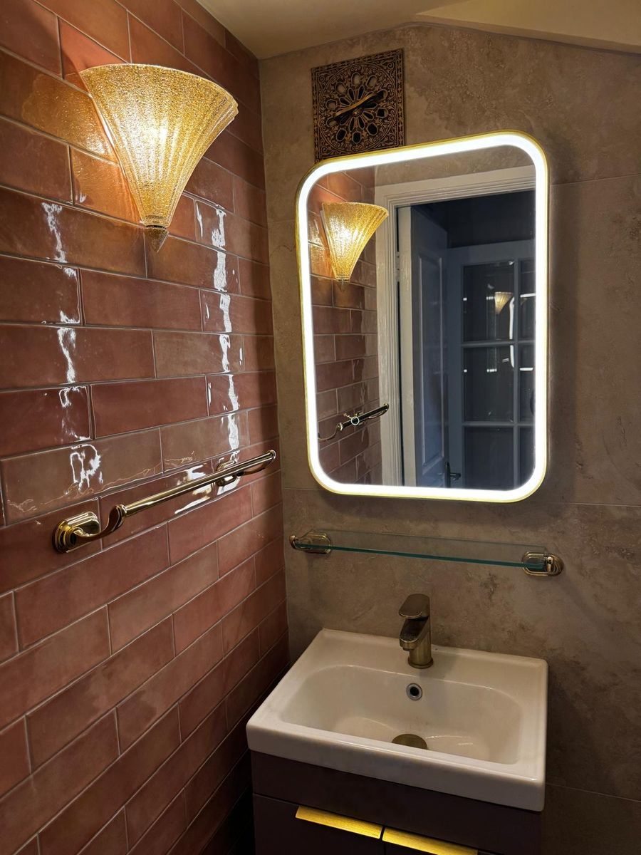 Guest cloakroom with tiled wall, illuminated mirror and basin unit