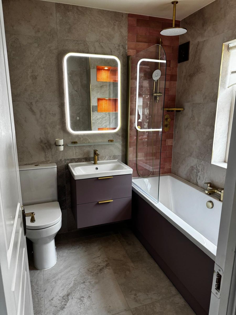 Completed family bathroom with wall hung vanity, bath and brass shower screen