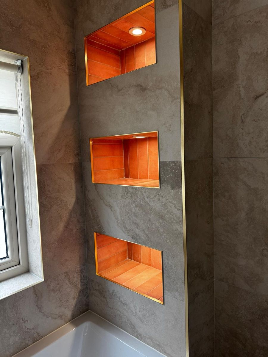 Three tiled shower niches with brass trim set into a tiled bathroom wall